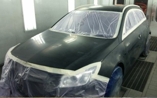 Bil klargjort for lakkering med plast og tape over glassruter